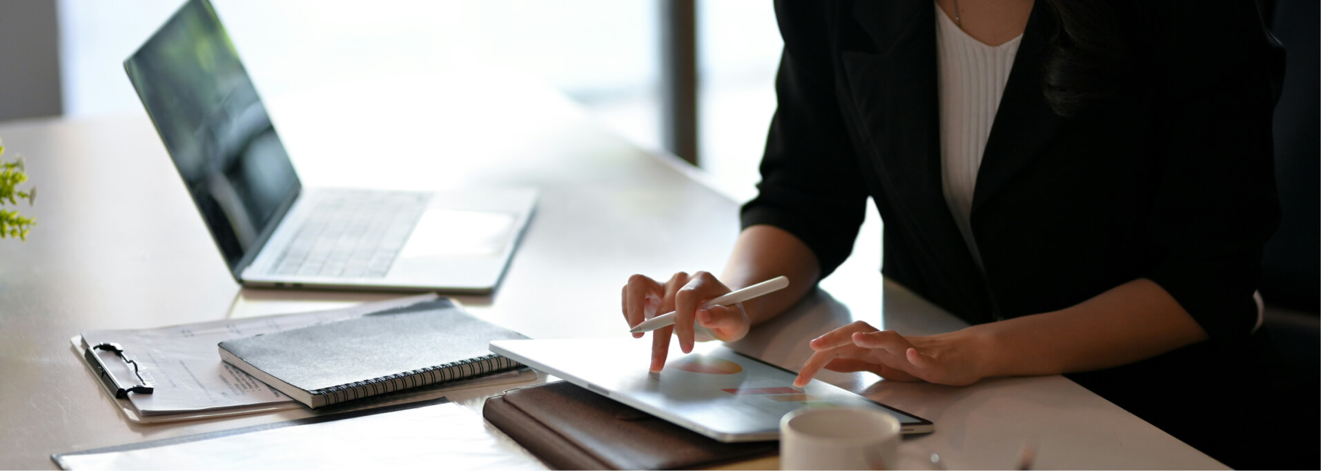 Eine Frau sitzt an ihrem iPad im Büro und arbeitet.